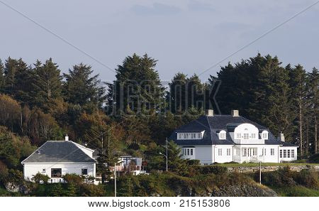 ROGALAND, NORWAY ON JULY 03. View of buildings on a hill next to the sea. Houses in evening lit on July 03, 2010 in Rogaland, Norway. Trees and gardens around. Editorial use.