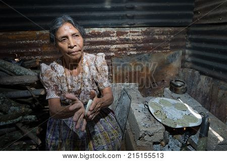 April 2, 2016 San Pedro la Laguna, Guatemala: an elderly tzutujil mayan woman is flattening tortillas in her palms beside wood fire