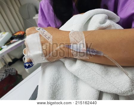 IV tube with saline solution on woman arm and needle holding knee leg with suffer