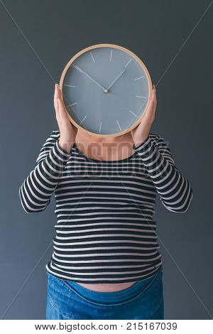 Pregnant female with vintage alarm clock expecting baby in third trimester of pregnancy