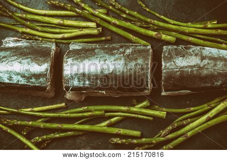 Food background with raw sawfish asparagus, lemon and herbs. Top view. Toned.
