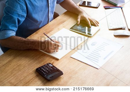 Calculate budget and business planning concept people couting revenue and expenditure by using calculator and laptop looking paper graph on desk in home office