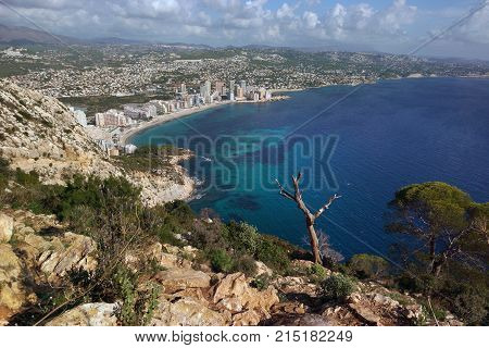 View From The Mountain Ifach On A Steep Stony Slope, The Blue Sea And Coastal Town Of Kalp On The Me