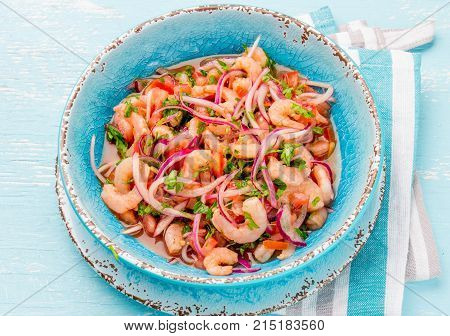 Ecuadorian shrimps ceviche sebiche with tomatoes in blue bowl, wooden blue background. Traditional ecuadorian colombian or mexican dish