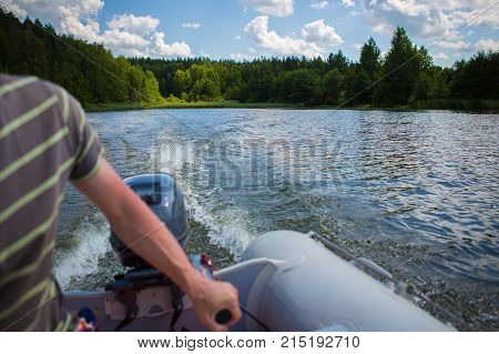Man driving a motor boat on a lake on a summer day