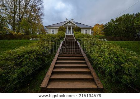 A wooden staircase leading to the old landed Russian house on a hill. A. Pushkin House-Museum in Mikhailovskoye Estate. The Pushkin Mountains. Pskov region. Russia. Autumn evening.