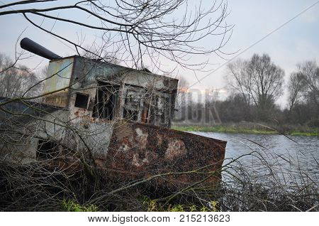 A dilapidated barge moored on the river bank