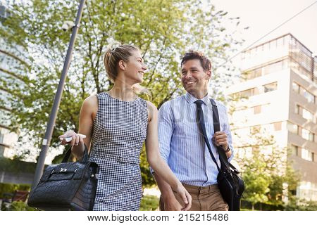 Businessman And Businesswoman Walk to Work Through City Park