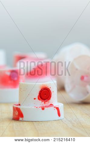 Several Plastic Nozzles From A Paint Sprayer That Lie On A Wooden Surface Against A Gray Wall Backgr