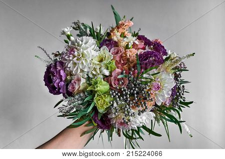 Bride holding a Wedding Bouquet in a Hand with colorful red, pink and white petals.