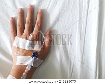 Patient hand with the tube of normal saline infusion on white cloth background