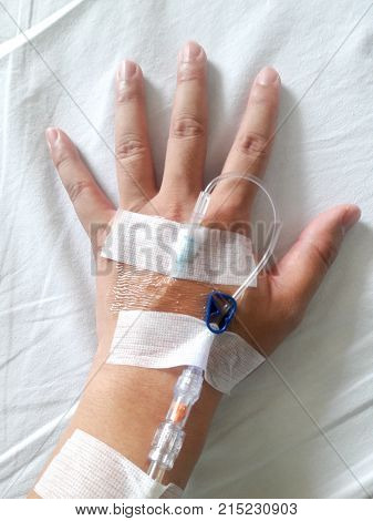 Patient hand with the tube of normal saline infusion on white cloth background
