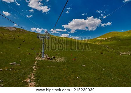 Aerial ropeway high in the mountains of Caucasus with grass plains and cow pastures in the background