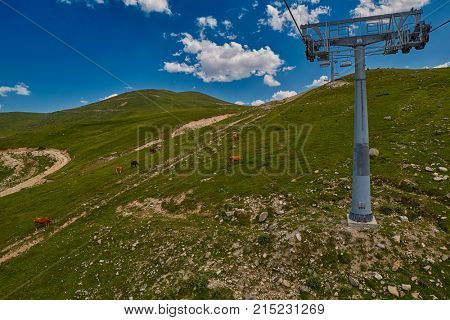 Aerial ropeway high in the mountains of Caucasus with grass plains and cow pastures in the background
