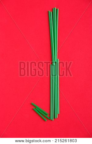 Letter J of plastic cocktail tubes on a red background.