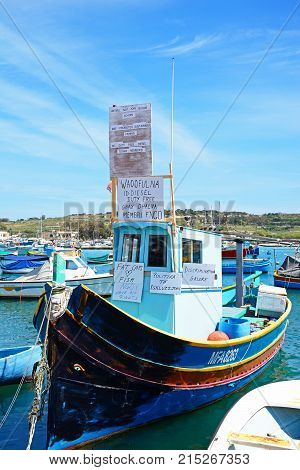MARSAXLOKK, MALTA - APRIL 1, 2017 - Traditional Maltese Dghajsa fishing boat in the harbour with protests against MAF Marsaxlokk Malta Europe, April 1, 2017.