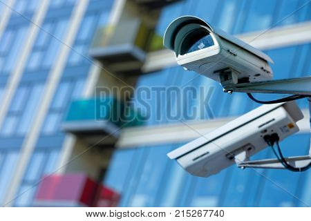 Cctv Security Camera In A City With Blury Business Building On Background