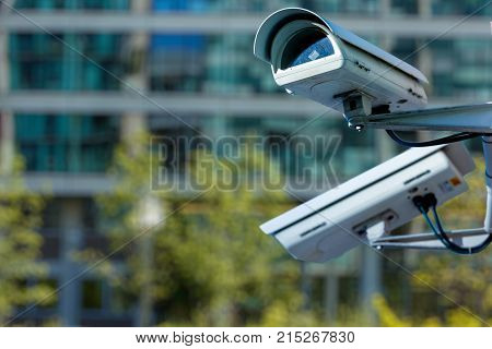 Cctv Security Camera In A City With Blury Business Building On Background