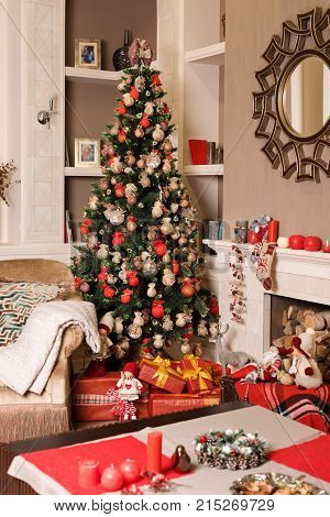 Cozyness And Home Comfort. Sofa Near The Decorated Christmas Tree And Fireplace With Firewood. Winte