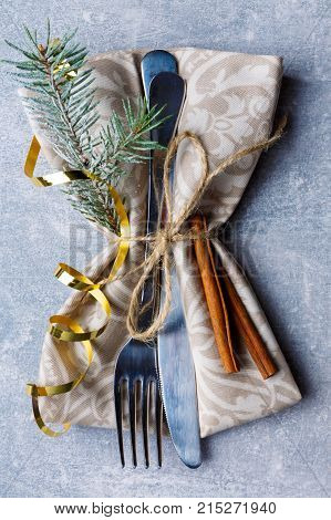 Serving in the napkin of cutlery decorated with a Christmas tree branch and cinnamon sticks. Close-up. View from above. Indoors.