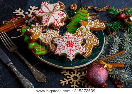 Delicious sweet Christmas gingerbreads of different shapes in multi-colored sugar glaze on a festive table set.