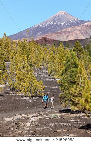 Hiking landscape Teide, Tenerife. Young couple hikers in Arenas Negras dramatic volcanic scenery with Teide in the background. Tenerife, The Canary Islands, Spain.