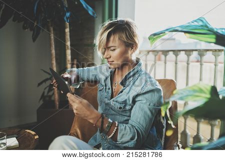 Smiling young woman wearing casual clothes and using electronic device while spending relax time in vacation travel.Attractive woman owner communicating on digital tablet.Blurred background
