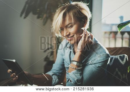Smiling young woman wearing casual clothes and using electronic device while spending relax time in vacation travel.Attractive woman owner communicating on digital tablet.Blurred background