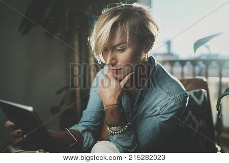 Smiling young woman wearing casual clothes and using electronic device while spending relax time in vacation travel.Attractive woman owner communicating on digital tablet.Blurred background
