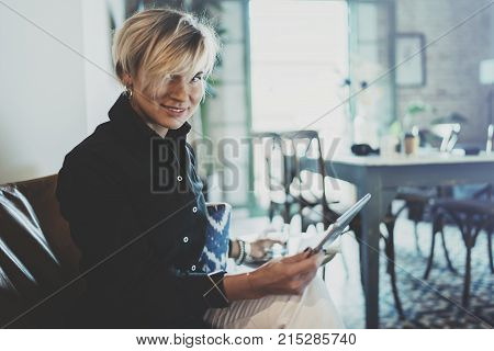 Smiling young woman wearing casual clothes and using electronic device while spending relax time in vacation travel.Attractive woman owner communicating on digital tablet.Blurred background