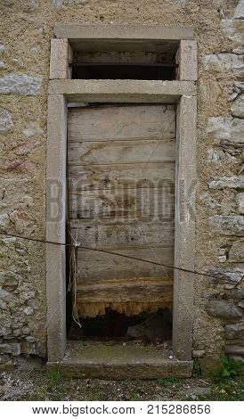 An old wooden door in a derelict building the historic hill village of Erto in Friuli Venezia Giulia north east Italy