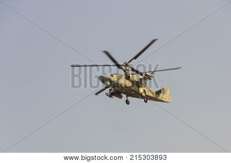 Green Helicopter Flies Against The Blue Sky