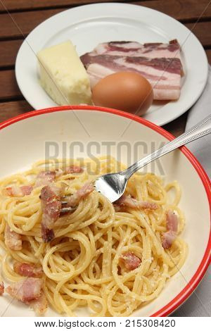 spaghetti carbonara into plate, with egg, chees and bacon