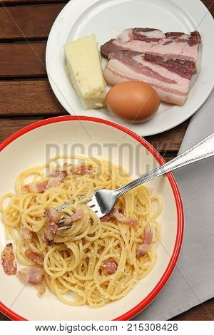 spaghetti carbonara into plate, with egg, chees and bacon
