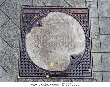 Hanover, Germany /Germany - November 12 2017: manhole on the sidewalk in Hanover with yellow leaves on it in autumn day
