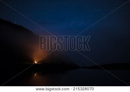 Landscape on the shore of the lake in the Carpathians mountains at the night with bonfire