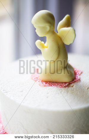 chocolate angel on a white cake and pink lace