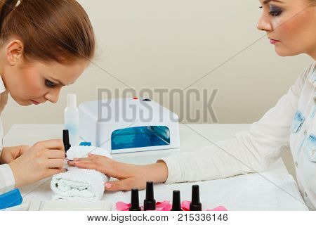 Relaxing time and wellness day concept. Blonde elegant woman visiting professional manicurist salon. Beautician makes perfect nails to client.