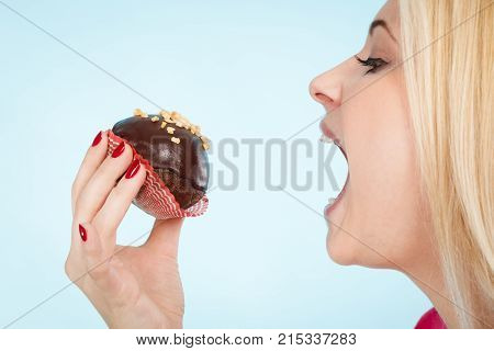 Diet sweets food concept. Woman holding delicious chocolate cupcake with peanut frosting about to take bite
