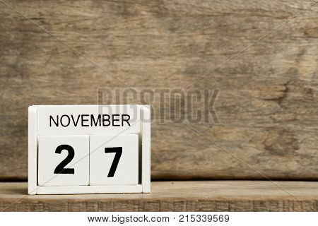 White block calendar present date 27 and month November on wood background