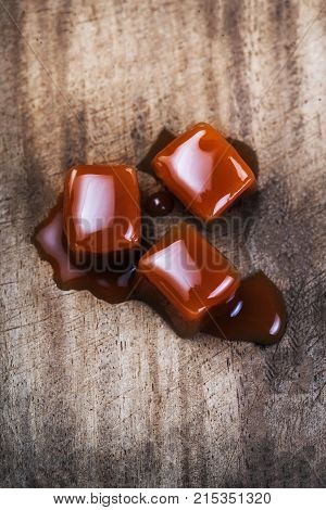 Organic caramel candies and caramel sauce on wooden background Golden Butterscotch toffee caramels