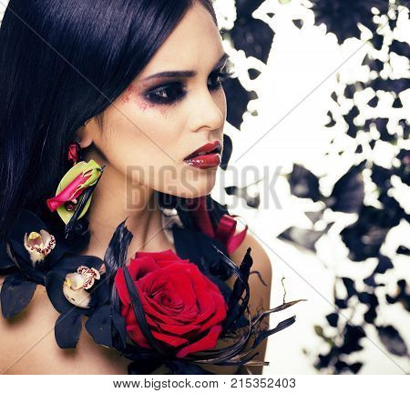 pretty brunette woman with rose jewelry, black and red, bright make up kike a vampire closeup red lips, halloween concept