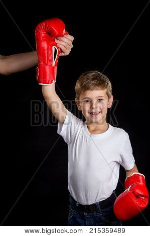The little winner. Extremely happy little boxer with right hand up in red boxing gloves. Boxing coach support