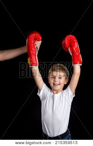 The little champ with coach support. Extremely happy little boxer with hands up in red boxing gloves.
