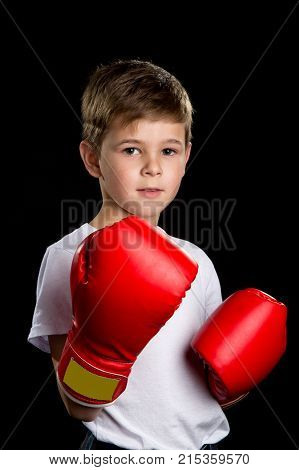Boy portrait in the red boxing gloves on the black background.