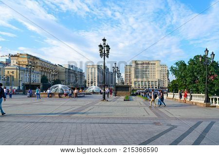 MOSCOW RUSSIA - JULY 23 2016: Unknown people rest on Manezhnaya square. Four Seasons Hotel Moscow 5* (formerly - Moscow Hotel) and building of State Duma