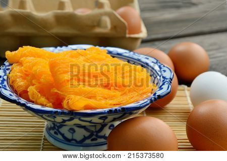 Golden egg strip is Thai desserts made from eggs with Thai style bowl on wooden background