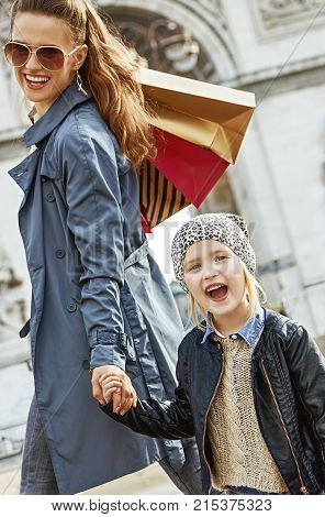 Stylish autumn in Paris. smiling trendy mother and child with shopping bags near Arc de Triomphe in Paris France