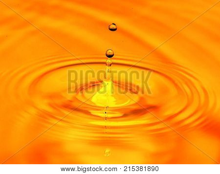 a drop of water falls in a golden water. macro .