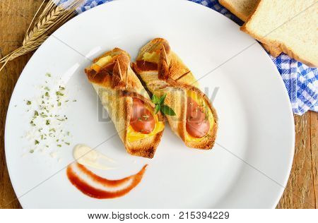 Toasted Hot Dogs and Cheese on white dish and wheat with fresh toast on wooden background